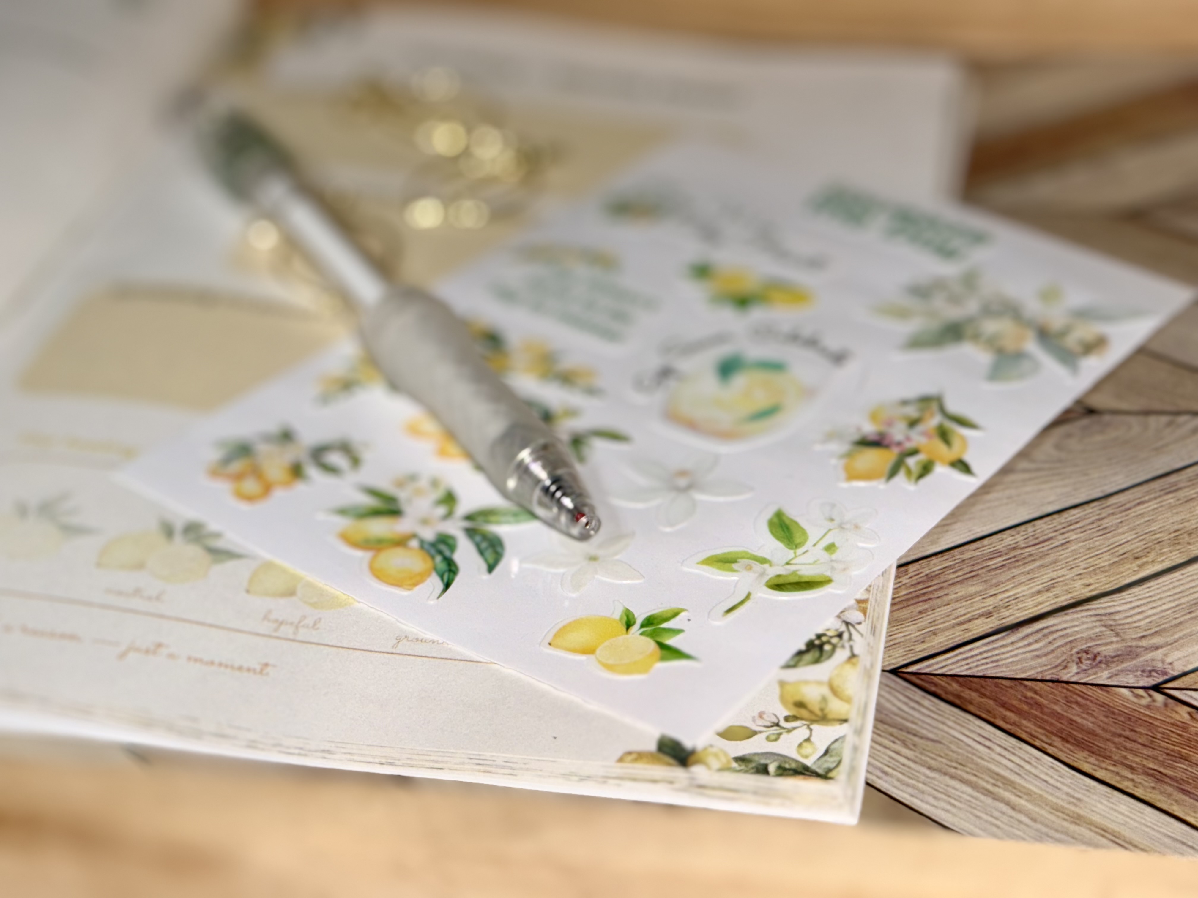 Close-up of lemon-themed watercolor stickers and silver pen on an open notebook, representing the joy of creative journaling
