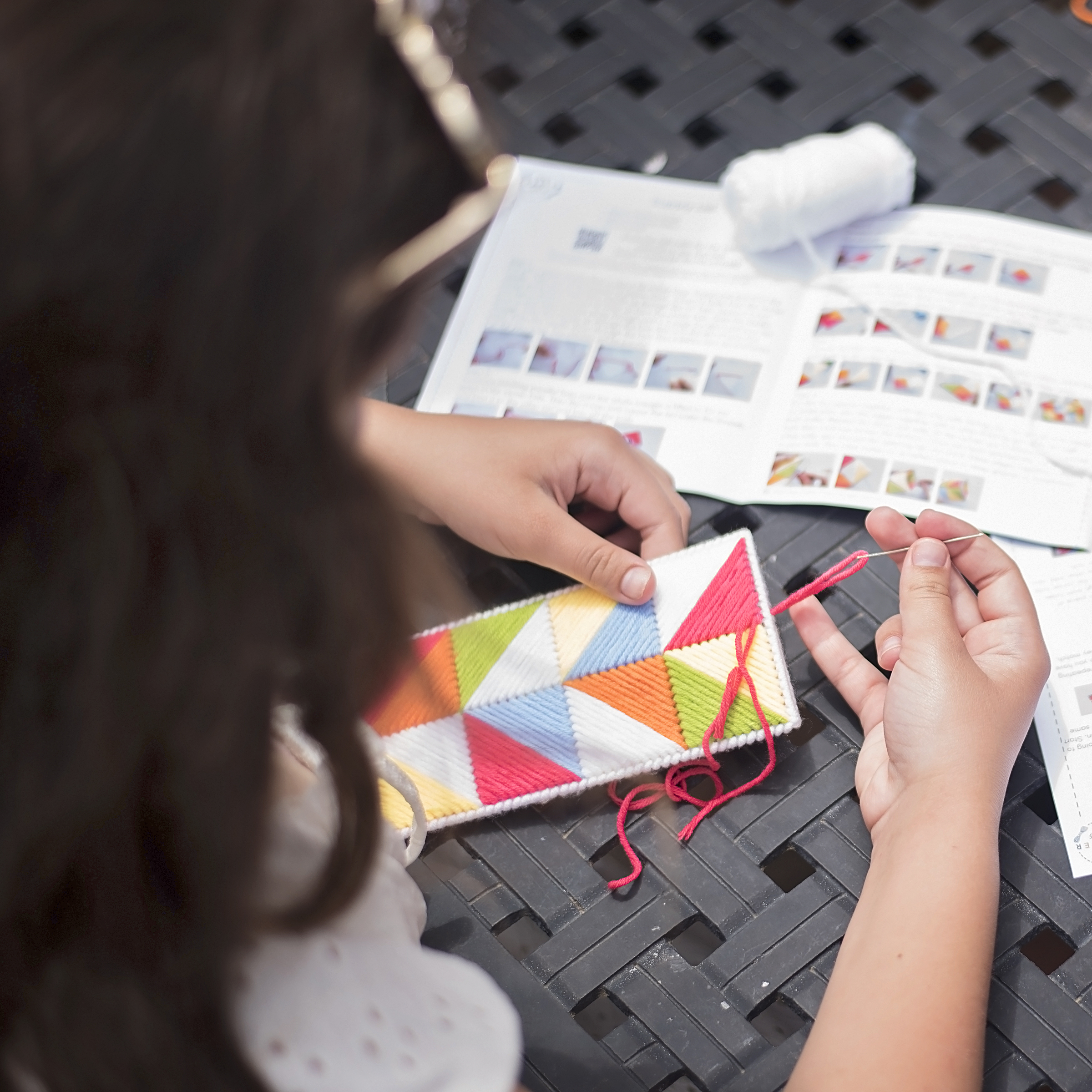 Child following step-by-step instructions to weave a handmade craft project