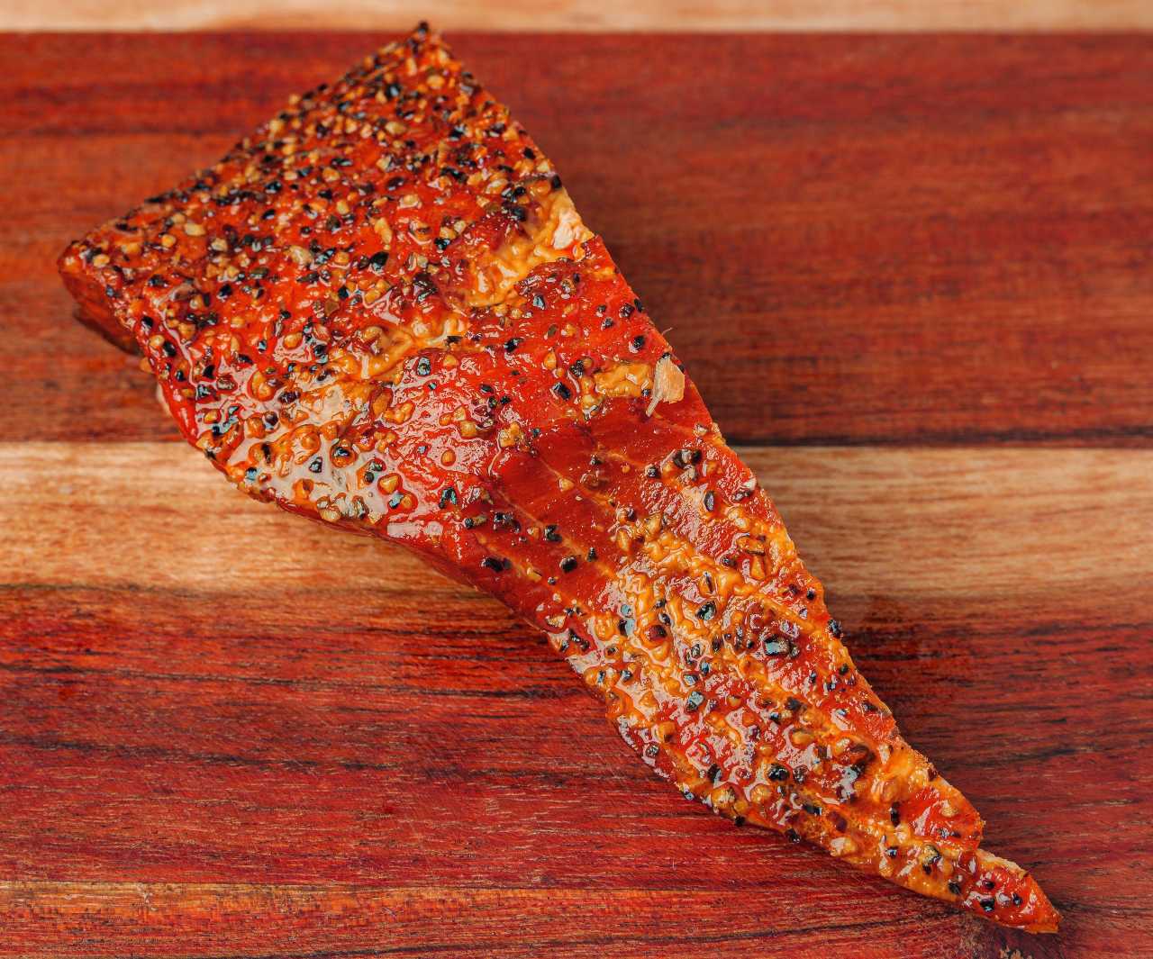 Vacuum-sealed smoked King Salmon fillet with red Long House Native label on rustic dark wood background