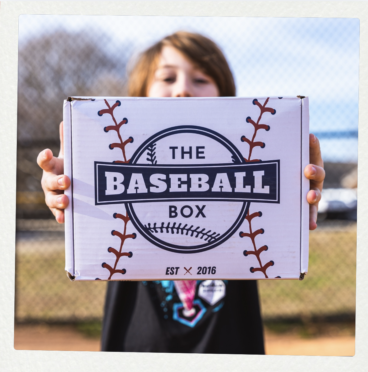 Young baseball player holding The Baseball Box and a Wilson glove