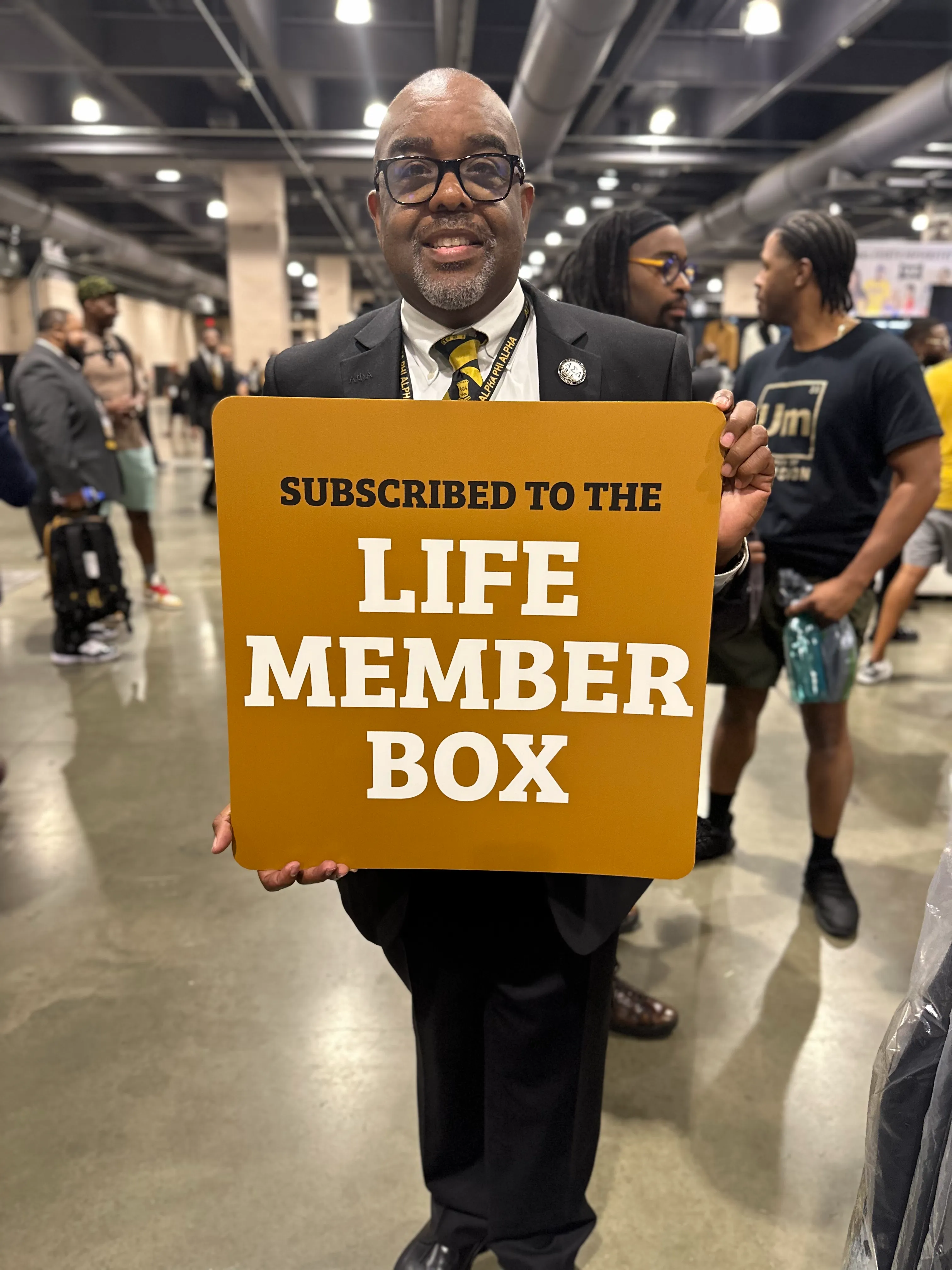 Alpha Traditions member showcasing the full subscription box collection at a fraternity gala