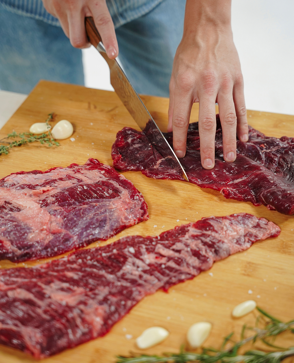 Butcher slicing grass-fed beef on a wooden board