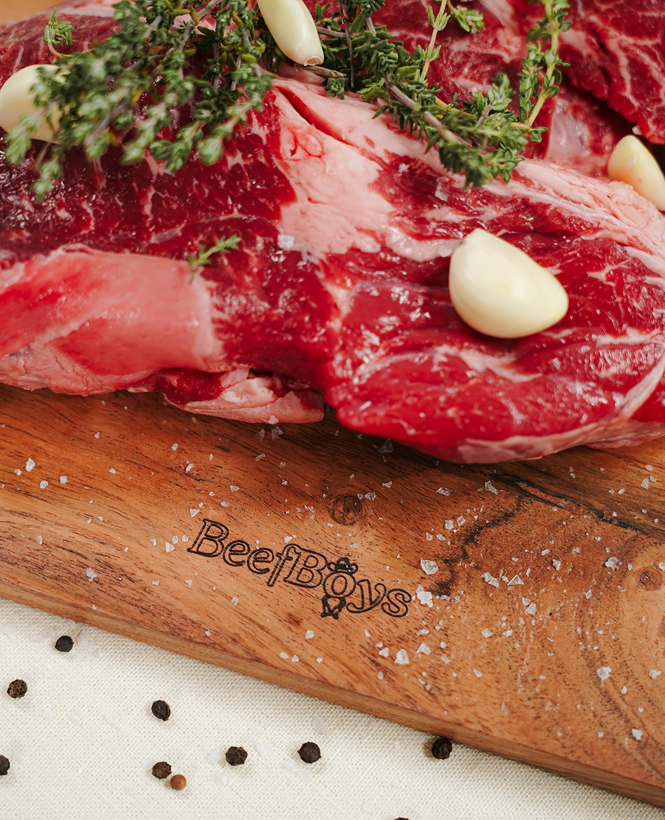 Raw ribeye with garlic and thyme on a wooden board